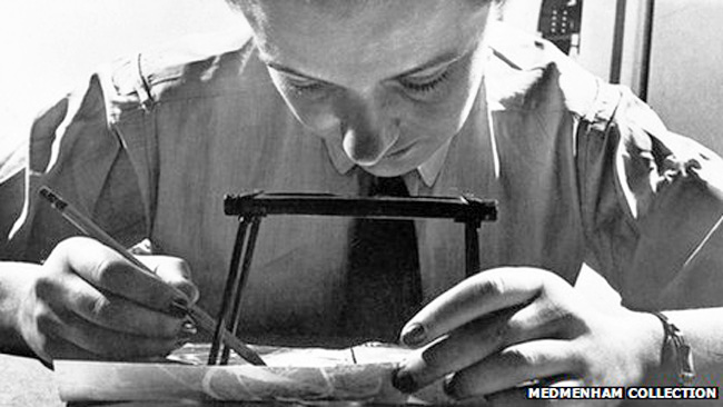 A WAAF photographic interpreter examining reconnaissance photographs with a stereoscope